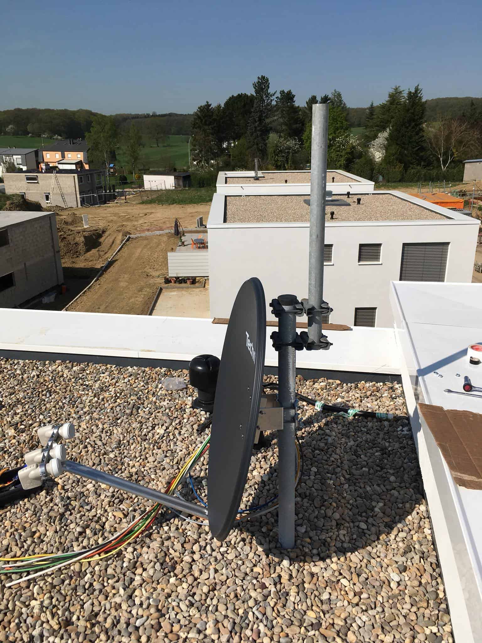 Parabole installée sur un mât en toiture